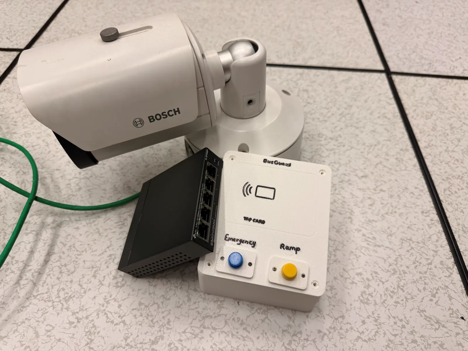 Prototype hardware: a white Bosch bullet camera, a black PoE network switch and a 3D-printed BusGuard box with a card reader and Emergency and Ramp buttons